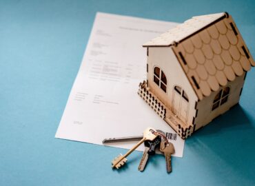 Maquette de maison et clés posées sur un document lié à l’immobilier 2026.
